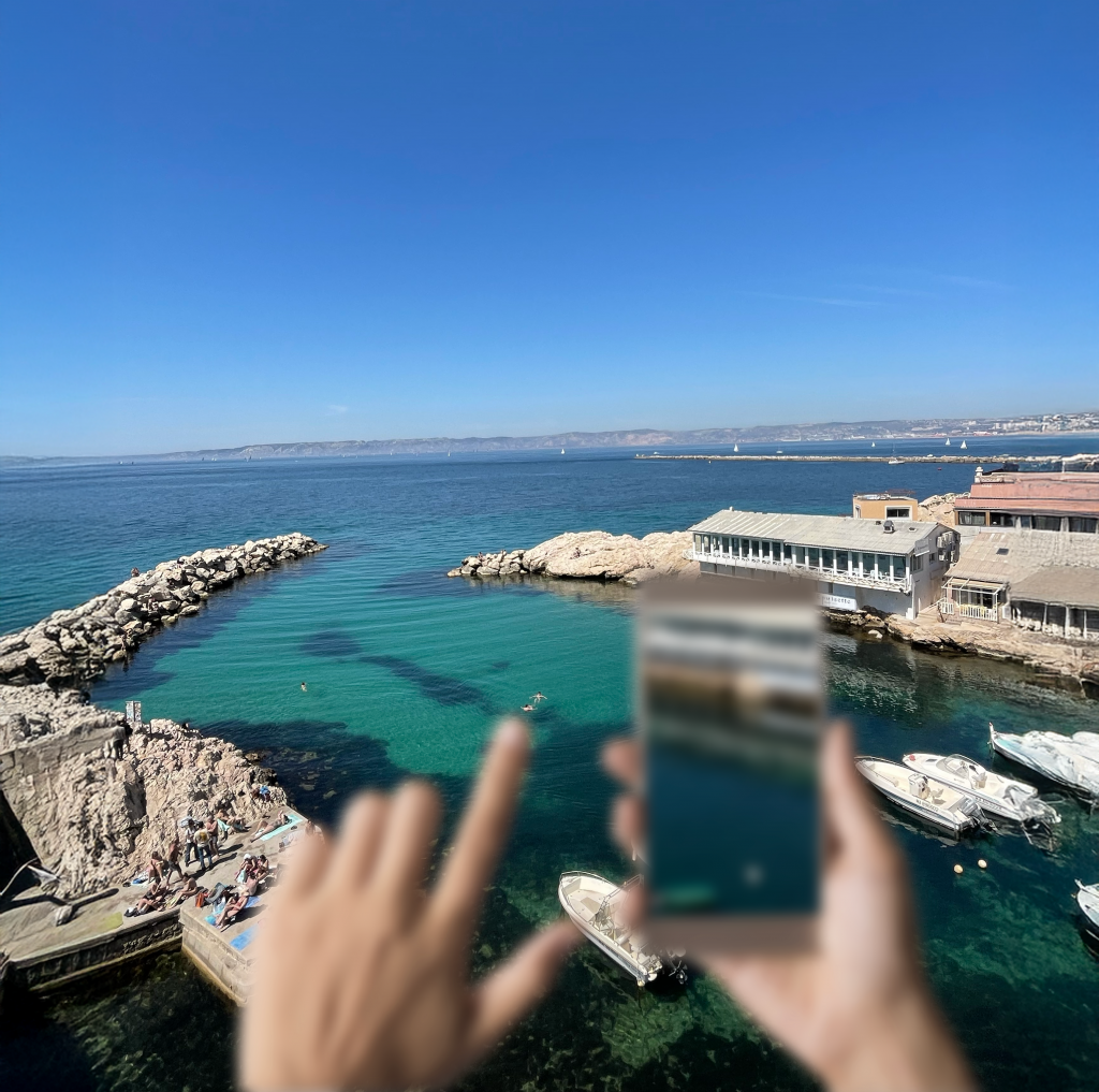 Main tenant un téléphone flou la mer, symbolisant l'hypermétropie