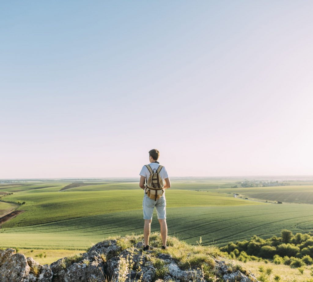 Homme avec un sac à dos regardant un paysage de collines - Chirurgie laser des yeux