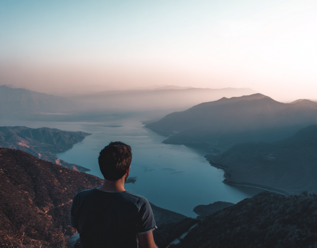 Homme de dos admirant une vue panoramique dégagée depuis la montagne, illustrant la clarté visuelle retrouvée après une chirurgie réfractive au laser.