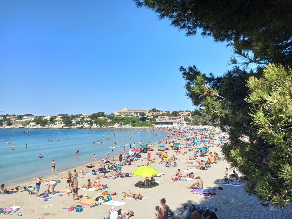 Vue d'une plage à Martigues avec parasols et baigneurs.