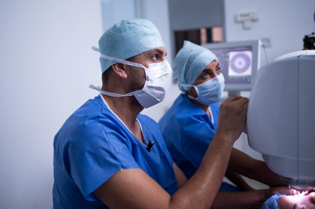 Une ophtalmo et un optométriste en chirurgie réfractive, concentrés sur un appareil médical.
